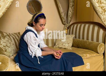 Dutch Master portrait de style d'une belle jeune femme en costume renaissance authentique allongé sur un luxueux lit à baldaquin antique dans une chambre d'or d'un Banque D'Images