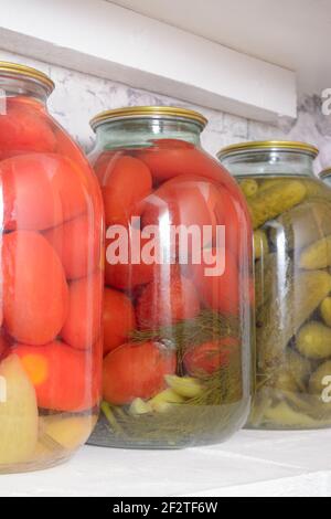 Tomates marinées et concombres en pots sur la tablette. Préparation des légumes à la maison. Gros plan, mise au point sélective. Banque D'Images