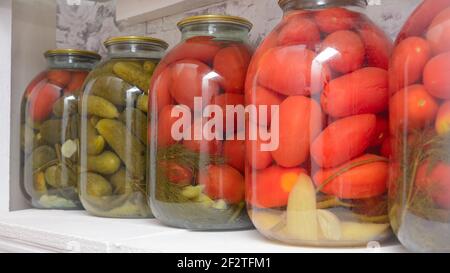 Tomates marinées et concombres sur les étagères de rangement. La récolte des légumes à la maison pour l'hiver. Grand format, durée de vie panoramique, mise au point sélective. Banque D'Images