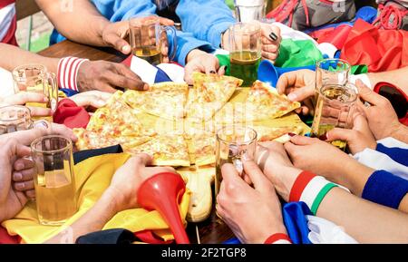 Vue du dessus des mains multiraciales du supporter des amis du football partage de pizza margherita au restaurant Banque D'Images