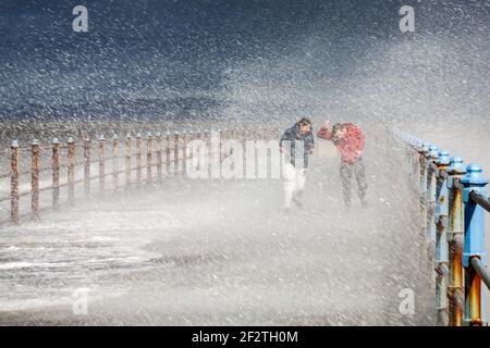 Heysham Lancasahire, Royaume-Uni. 13 mars 2012. Ce matin, un jeune couple se fait prendre dans une vague s'écrasant au-dessus du brise-lames à High Tide à Morecambe crédit: PN News/Alay Live News Banque D'Images