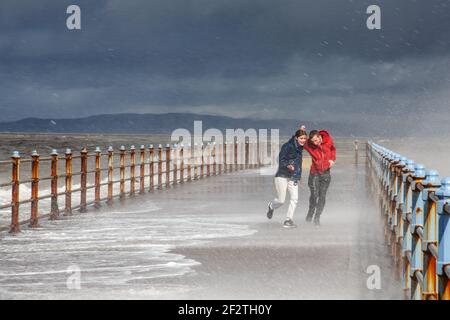 Heysham Lancasahire, Royaume-Uni. 13 mars 2012. Ce matin, un jeune couple se fait prendre dans une vague s'écrasant au-dessus du brise-lames à High Tide à Morecambe crédit: PN News/Alay Live News Banque D'Images