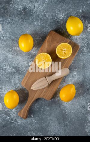 Citrons tranchés et entiers avec alésoir en bois Banque D'Images