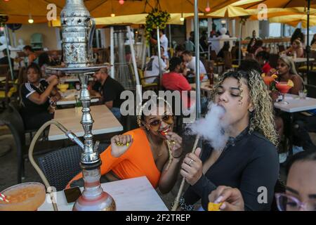 Miami, États-Unis. 11 mars 2021. Malgré la pandémie du coronavirus, les briseurs de printemps Karsyn McLeod et Zayasha Fowler, tous deux 21 ans, passent du temps à manger à l'extérieur et à des bars Hookah le long d'Ocean Drive sur South Beach à Miami, le 12 mars 2021. (Photo d'Al Diaz/Miami Herald/TNS/Sipa USA) crédit: SIPA USA/Alay Live News Banque D'Images