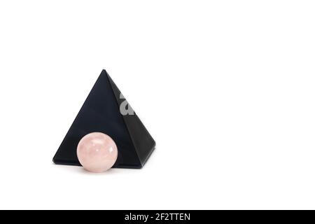 Pyramide obsidienne noire et boule de quartz rose. Concept Reiki. Isolé sur fond blanc, espace de copie. Banque D'Images