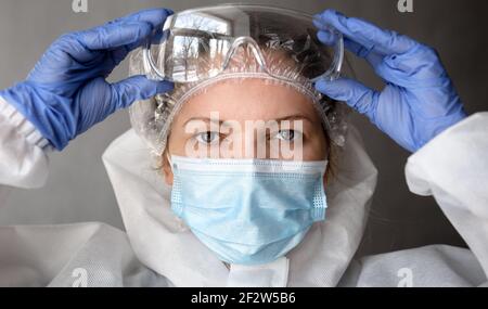 Médecin ou infirmière en costume d'EPI de COVID-19, portrait d'une femme médecin portant des lunettes de protection et un masque médical pour le visage en raison d'une pandémie de coronavirus. C Banque D'Images