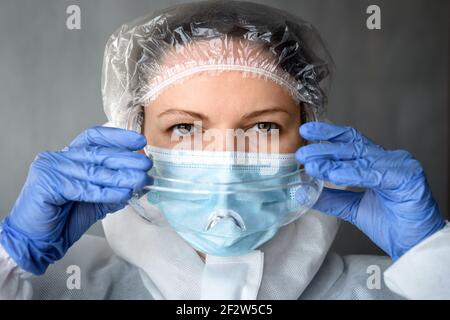 Portrait d'un médecin en costume d'EPI médical, une infirmière féminine met des lunettes de protection pendant la pandémie de COVID-19, une femme médecin portant un masque facial en raison de la cor Banque D'Images