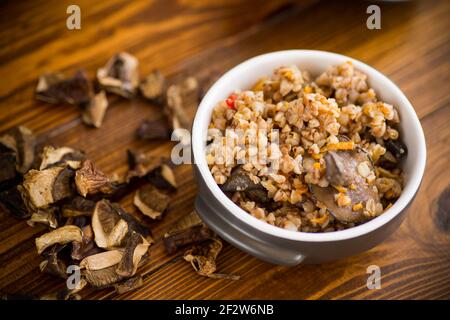 sarrasin bouilli avec champignons de forêt biologique séchés dans une céramique bol sur une table en bois Banque D'Images