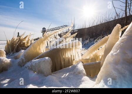 Plantes couvertes de glace sur le rivage du lac gelé en hiver. Après-midi d'hiver frais sur la promenade du bord de mer, au coucher du soleil et dans les buissons gelés. Glaçons allumés par le soleil Banque D'Images