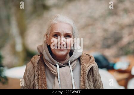 Portrait d'une femme âgée souriante aux cheveux gris à l'extérieur Banque D'Images