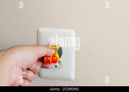 Le testeur de prise électrique, également appelé testeur de prise, est un petit appareil utilisé pour confirmer le câblage et le courant électrique corrects dans une prise. Deux jaunes Banque D'Images