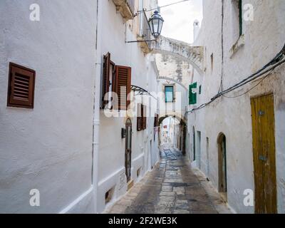 Pittoresque ruelle pavée avec des maisons blanches traditionnelles dans l'ancienne ville d'Ostuni, région des Pouilles, sud de l'Italie Banque D'Images