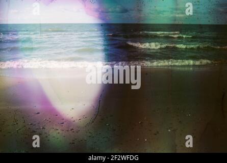 Photo endommagée et floue du bord de mer avec taches et rayures. Photo vieilli vintage. Banque D'Images