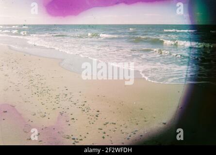 Photo endommagée et floue du bord de mer avec taches et rayures. Photo vieilli vintage. Banque D'Images