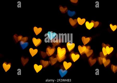 Saint-Valentin grunge coeur lumière fond. Or jaune et bleu coeur en forme de coeur sur fond noir lumière colorée bokeh pour la décoration Valentin Banque D'Images
