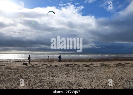 Troon, Ayrshire, Écosse, Royaume-Uni. 13 mars 2021. Un cerf-volant se prépare à profiter des vents forts sur le rivage à Troon Beach alors que les nuages de pluie foncés se déplacent rapidement au-dessus de la tête. Banque D'Images