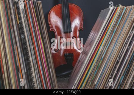 une pile de vieux disques en vinyle devant un violine Banque D'Images