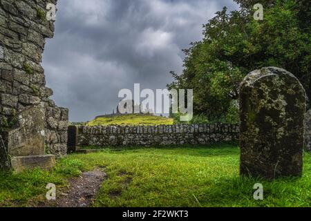 Vue à travers les ruines anciennes de l'abbaye de Hore et tombe sur le château Rock of Cashel avec ciel sombre et spectaculaire de tempête en arrière-plan, comté de Tipperary, Irlande Banque D'Images