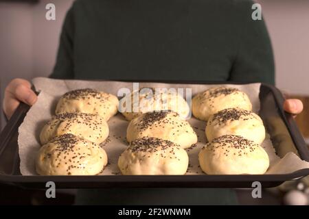 la pâte à levure prête à faire des petits pains faits maison est sur la table, entre autres ingrédients pour cuire du pain. une femme prépare des pâtisseries, soupir de la farine Banque D'Images