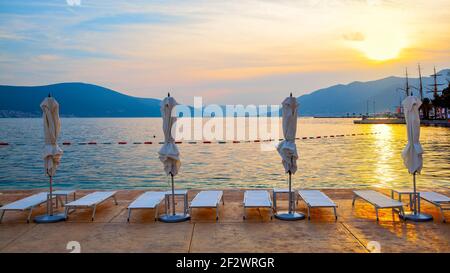 Plage au bord de la mer avec parasoles pliés au coucher du soleil, Tivat, Monténégro. Paysage Banque D'Images