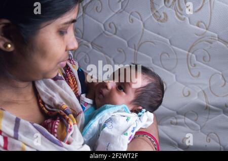 Un nouveau-né mignon regarde sa mère sur les genoux de sa mère en gros plan. Bébé Sweet Little d'un mois. Ethnie indienne. F