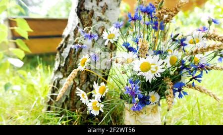 Paysage rustique avec bouquets simples de fleurs sauvages. Un joli bouquet de pâquerettes, camomille, cornflowers et épis de blé dans un vase en céramique contre le TH Banque D'Images