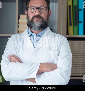 Portrait d'un médecin adulte avec barbe et sourire - doc confiant dans le fond blanc de studio - concept de soins de santé et visite du patient - uniforme de l'hôpital ma Banque D'Images