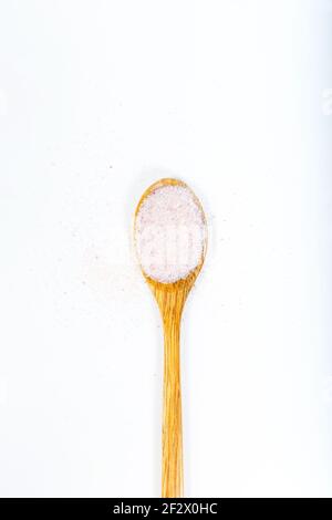 Sel de l'Himalaya rose dans une cuillère en bois isolée sur fond blanc. Banque D'Images