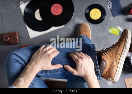 Main pour homme sur la jambe en Jean avec de vieilles chaussures de voyage en cuir. Détente et art musique concept de style de vie Banque D'Images