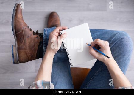 Main pour homme tenant un crayon et un carnet. Étudiant homme écriture ou dessin à la main au crayon Banque D'Images