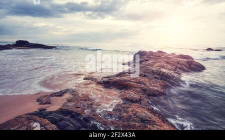 Coucher de soleil pittoresque sur une plage rocheuse, couleurs appliquées, Sri Lanka. Banque D'Images