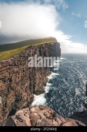 Îles Féroé Traelanipa la falaise rocheuse des esclaves s'élève au-dessus de l'océan à côté du lac Sorvagsvatn. Nuages et ciel bleu pendant le suommer sur le Banque D'Images