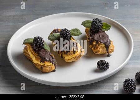 Eclairs français traditionnels au chocolat et aux mûres. Banque D'Images