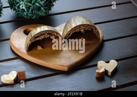 Demi-œuf de Pâques en tranches (ovo de Pascoa), avec double coquille farcie au caramel et aux biscuits, décorée de peinture dorée comestible. Sur un pl en forme de coeur Banque D'Images