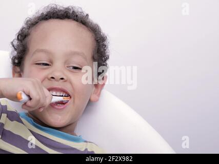 garçon se brossant les dents avec une brosse sur fond blanc photos Banque D'Images