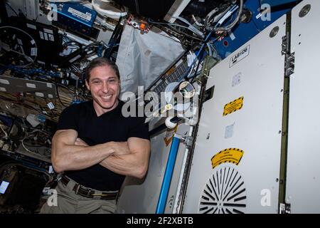 Michael Hopkins, astronaute de la NASA et ingénieur de vol de l'expédition 64, sourit alors qu'il pose à côté d'un distributeur de cassettes créé par des élèves du secondaire unis avec la NASA pour créer du matériel à bord de la Station spatiale internationale le 4 mars 2021 Earth Orbit. Banque D'Images