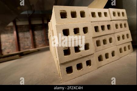 Petite pile de briques beige clair à l'intérieur. Vue rapprochée, inclinée, à angle bas. Faible profondeur de champ. Sol en béton vieux mur de briques en arrière-plan. Banque D'Images