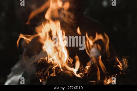 Jeune homme avec un match brûlant dans le feu sombre journal Banque D'Images