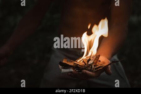 Jeune homme avec un match brûlant dans le feu sombre journal Banque D'Images