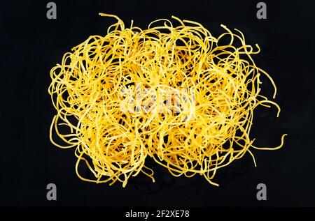 Pâtes de tagliatelle fraîches sur fond sombre, beaux longs rubans jaunes plats de pâtes crues Banque D'Images