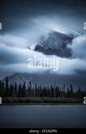 Un lever de soleil couvert et obscure obscurcit le mont Rundle au loin des lacs Vermilion, dans le parc national Banff, au Canada. Banque D'Images