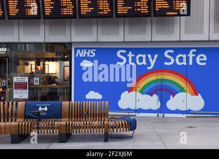 Hall isolé de la gare de London Bridge avec bancs en bois et affiche arc-en-ciel NHS Stay Safe . Banque D'Images