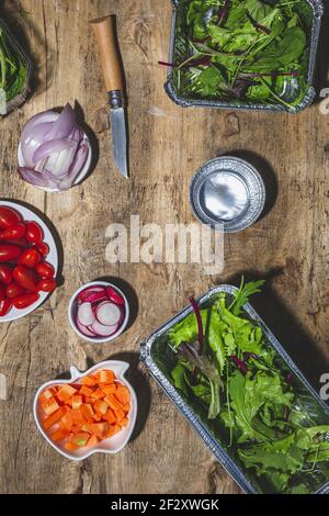 Vue de dessus composition de divers légumes frais dont la cerise radis tomates oignon et salade mixte feuilles sur table en bois Banque D'Images