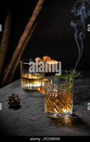 Verre de cristal de whisky à l'ancienne garni de fraîcheur zeste de romarin et d'orange sur une table noire Banque D'Images