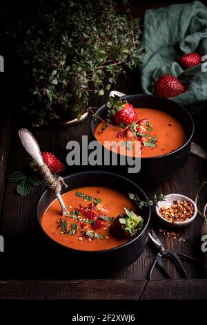 De la composition ci-dessus avec délicieux tomates maison et Gazpacho fraise soupe servie dans des bols sur une table rustique en bois Banque D'Images