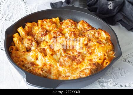 Gratin de macaroni aux boulettes de viande et sauce tomate à la mozzarella fromage préparé et servi dans une poêle à frire sur une table Banque D'Images
