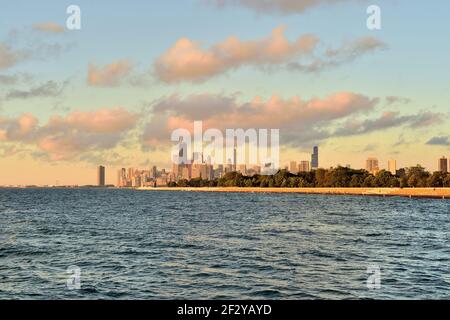 Chicago, Illinois, Illinois. Peu de temps après que le soleil a brisé l'horizon, la lumière a été projeté dans le ciel et les nuages au-dessus d'une partie de la ligne d'horizon. Banque D'Images