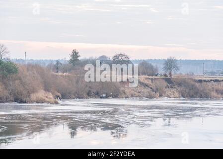 une rivière sinueuse qui est encore gelée mais la chaude l'air du ressort commence progressivement à fondre la couche épaisse de la glace et de l'eau se forment sur le Banque D'Images