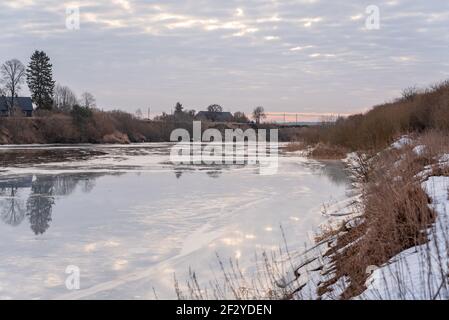 une rivière sinueuse qui est encore gelée mais la chaude l'air du ressort commence progressivement à fondre la couche épaisse de la glace et de l'eau se forment sur le Banque D'Images