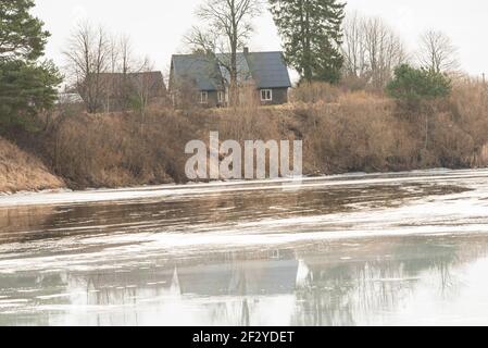 une rivière sinueuse qui est encore gelée mais la chaude l'air du ressort commence progressivement à fondre la couche épaisse de la glace et de l'eau se forment sur le Banque D'Images